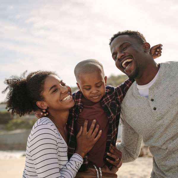 family of three laughing on beach