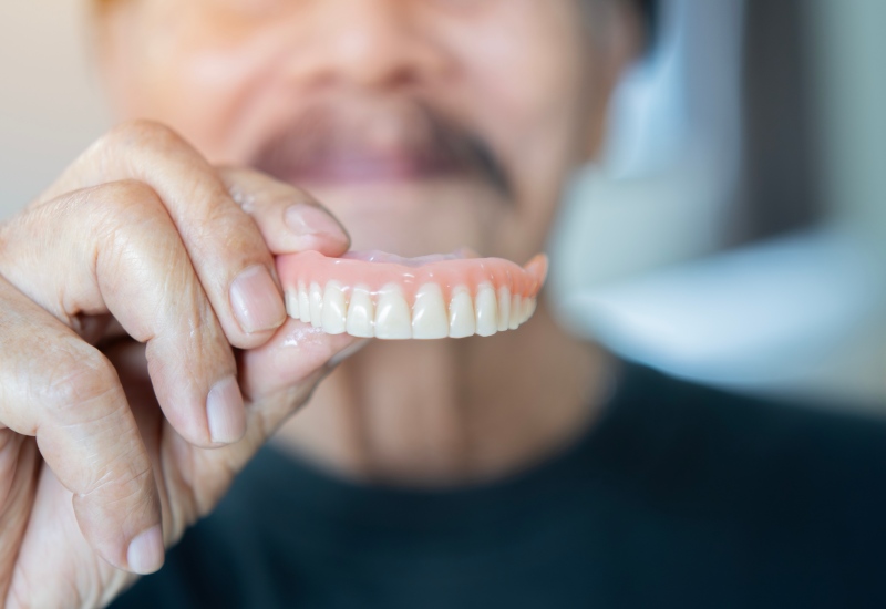Person holding dentures given by dentist in Arlington Heights, IL