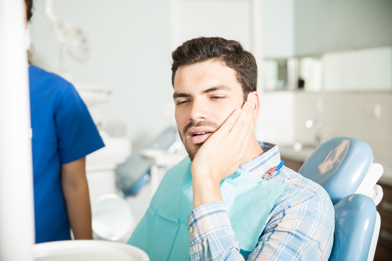 Patient holding jaw during dental visit for tooth sensitivity in Arlington Heights, IL