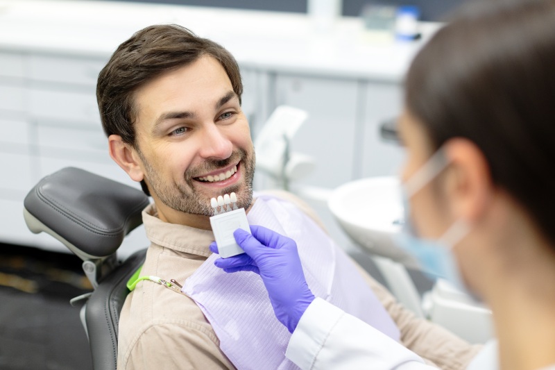 Patient comparing veneer shade samples during cosmetic dental consultation in Arlington Heights, IL